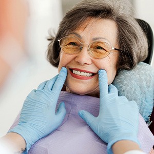 Dentist with blue gloves looking at senior woman's smile