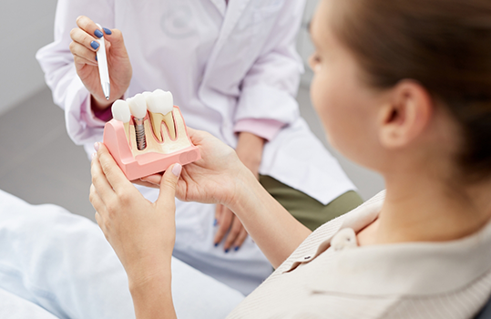 Dentist showing patient dental implant model