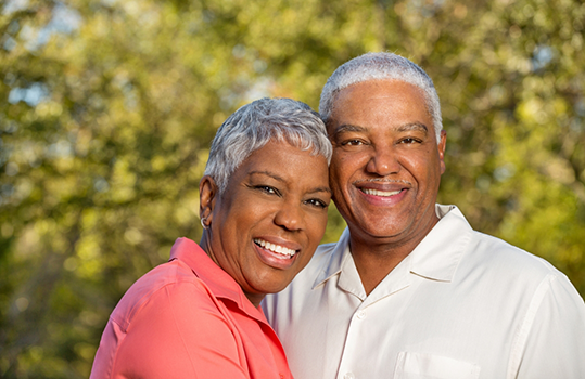 Senior couple standing and smiling together outside