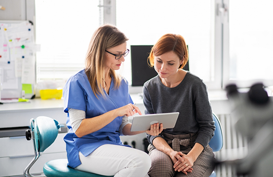 Female dentist showing patient something on a tablet