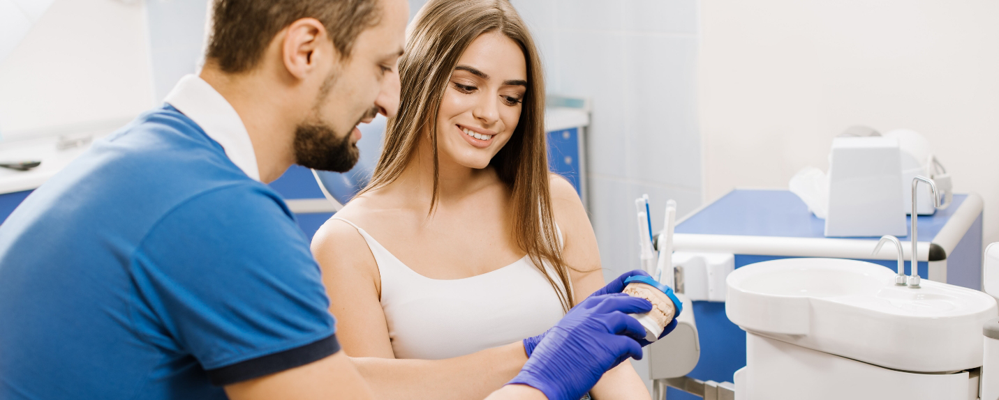 Dentist showing female patient model of teeth