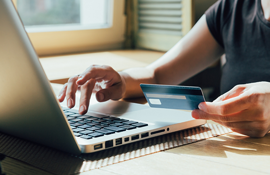 Man looking at credit card and typing on laptop