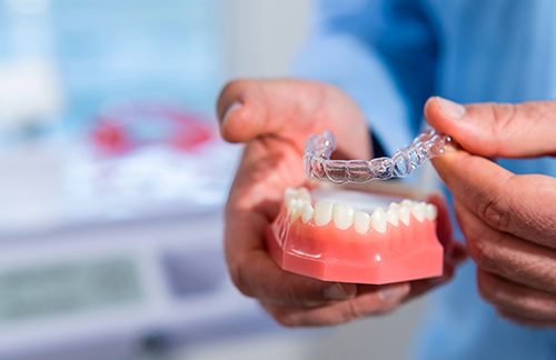 Dentist putting clear aligner on model of teeth