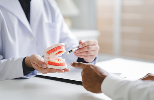 Dentist talking to patient and pointing to dentures