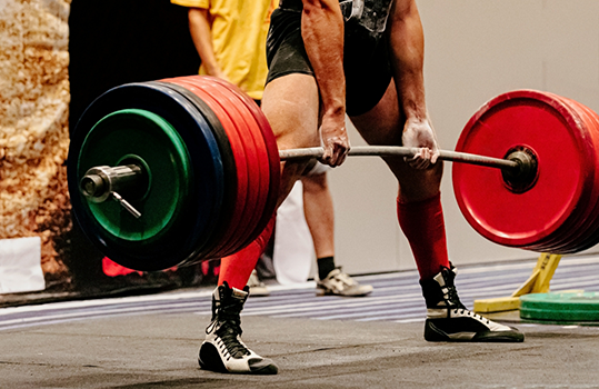 Close up of weightlifter picking up barbell