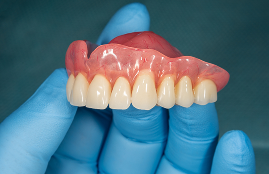 Close up of gloved hands holding denture