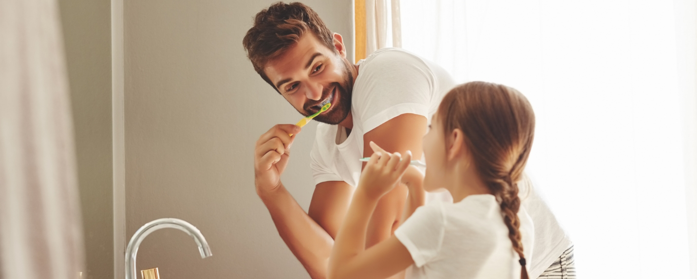 Father and daughter brushing teeth together