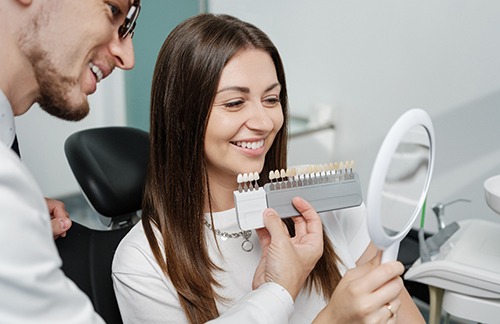 Dentist showing smiling patient shade scale