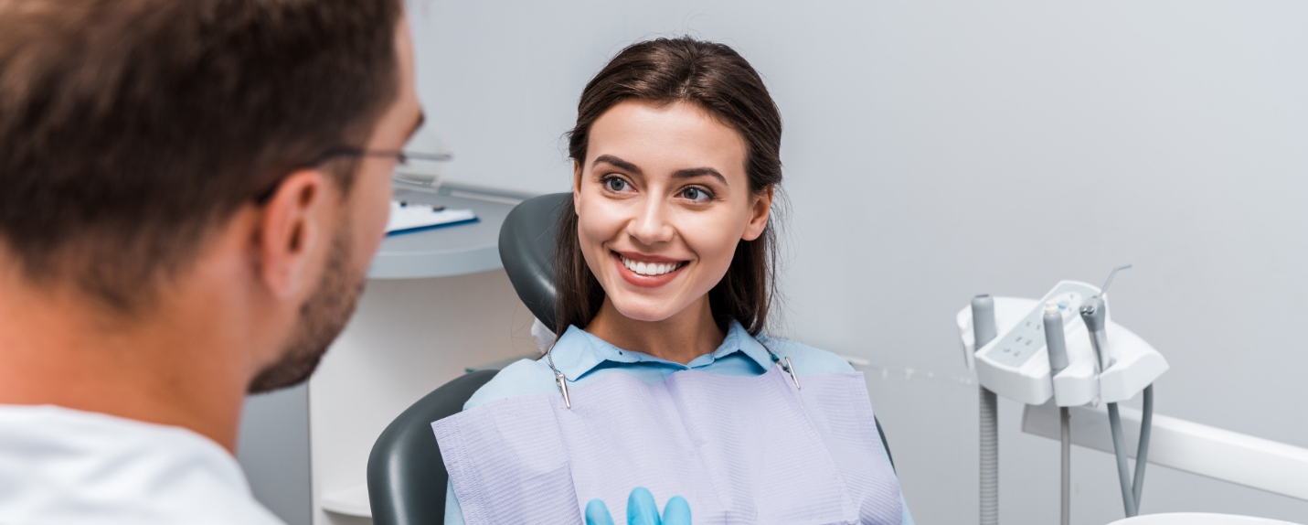 Woman smiling at dentist while sitting in dental chair